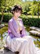 A woman in a purple kimono sitting on a rock by a pond.