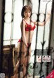 A woman in a red lingerie standing in front of a window.