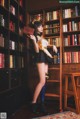 A woman standing in front of a bookshelf holding a book.