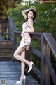 A woman in a floral dress posing on a wooden bridge.