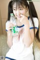 A young woman sitting on a couch holding a bottle of water.