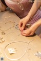 A woman is working on a necklace on a table.