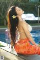 A woman in a bikini sitting by a swimming pool.