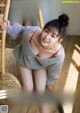 A woman in a gray sweater is sitting on a wicker chair.