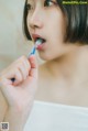 A woman brushing her teeth with a toothbrush.