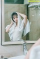 A woman wrapped in a towel standing in front of a mirror.