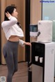 A woman standing next to a water dispenser in a room.