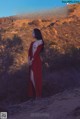 A woman in a red dress standing in front of the Hollywood sign.