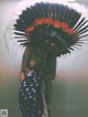 A woman wearing an indian headdress holding an American flag.