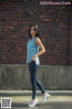 A woman standing in front of a brick wall.