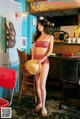 A woman in a red bikini standing in front of a bar.