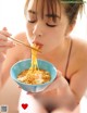 A woman eating a bowl of noodles with chopsticks.