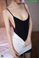 A woman in a black and white bodysuit posing on a bed.