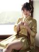 A woman in a yellow kimono sitting on a window sill.