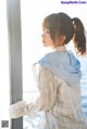 A woman standing by a window looking out at the ocean.