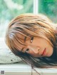 A woman with long brown hair laying on a window sill.