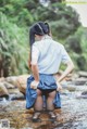 A woman in a school uniform is standing in a stream.