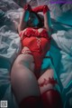 A woman in a red lingerie laying on a bed.