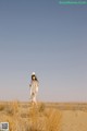 A woman standing in the middle of a desert.