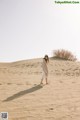 A woman standing on top of a sand dune.