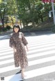 A woman in a floral dress crossing the street.