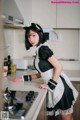 A woman in a maid outfit standing in a kitchen.