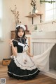 A woman in a black and white maid outfit posing for a picture.