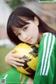 A young woman holding a soccer ball on a field.