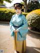 A woman in a blue and yellow hanbok standing in a park.