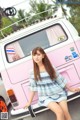 A woman sitting on the back of a pink and white van.