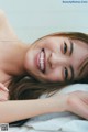 A woman laying on a bed smiling at the camera.