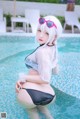 A woman in a bikini and sunglasses sitting in a pool.