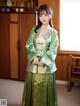 A woman in a green hanbok standing in front of a window.