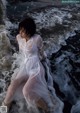 A woman in a white dress is sitting in the water.