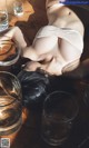 A woman laying on a wooden floor next to glasses of water.