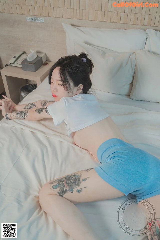 A woman laying on a bed with a tattoo on her arm.