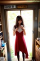 A woman in a red dress standing in front of a window.