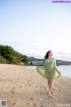 A woman in a green dress standing on a beach.