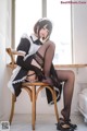 A woman in a maid outfit sitting on a chair.