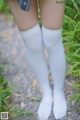 A close up of a person wearing white knee high socks.