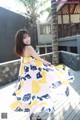A woman in a colorful dress standing on a wooden deck.