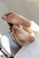 A woman laying on top of a bed with her feet up.