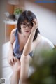 A woman wearing glasses sitting on a bed.