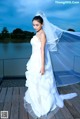 A woman in a wedding dress standing on a dock.